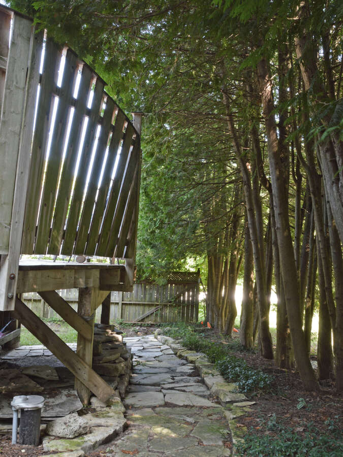 Stone walkway with access to under-deck storage, leading to the north side of the house.