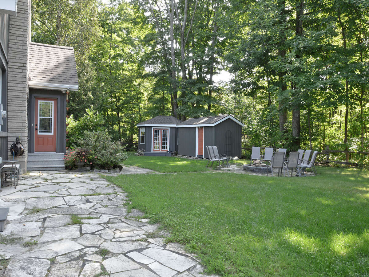 Side entrance with spacious yard, cozy fire pit area, storage shed, and cabana.