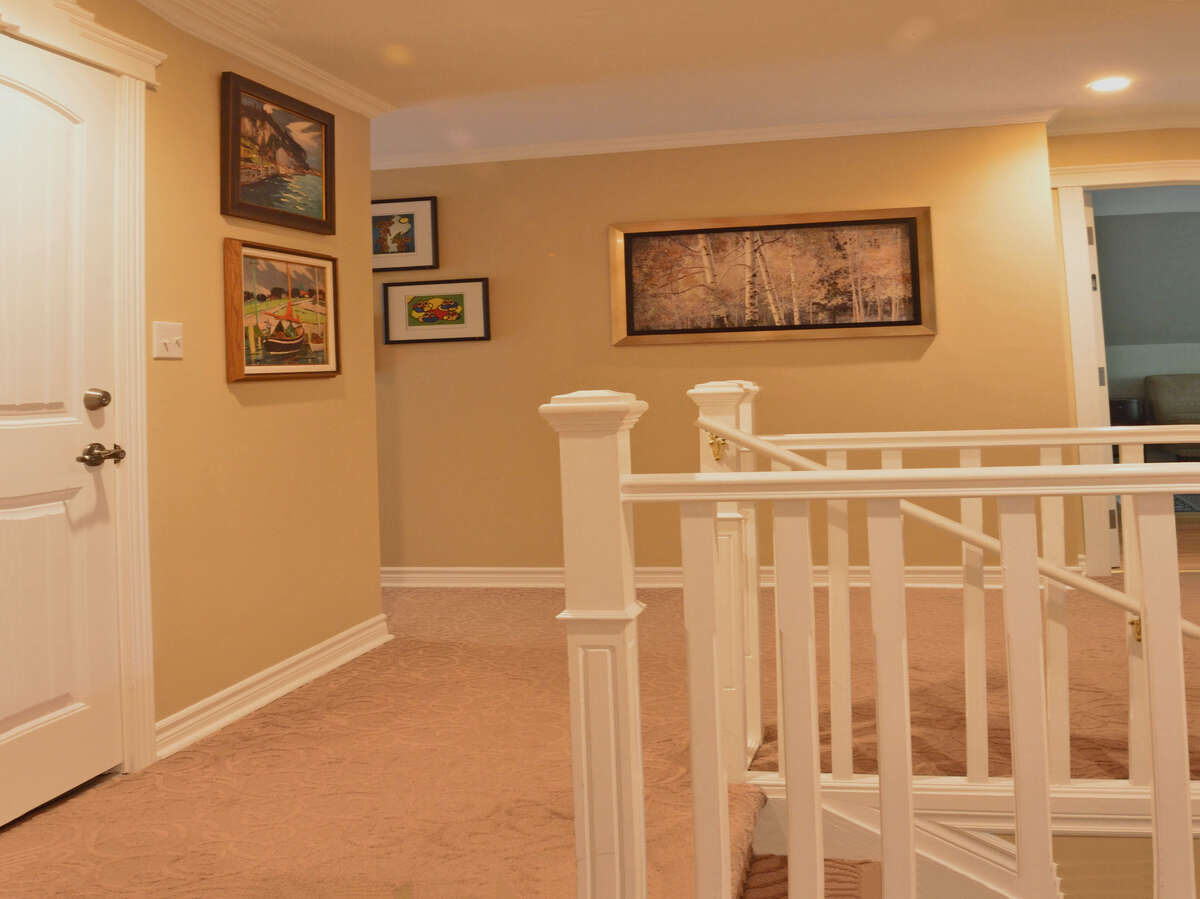 Carpeted upstairs hallway with warm tones and elegant decor, connecting all bedrooms and bathrooms.