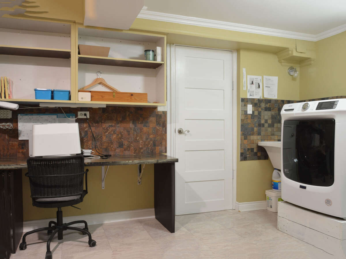 Versatile laundry room featuring a sewing area, steam closet, and ample storage space.
