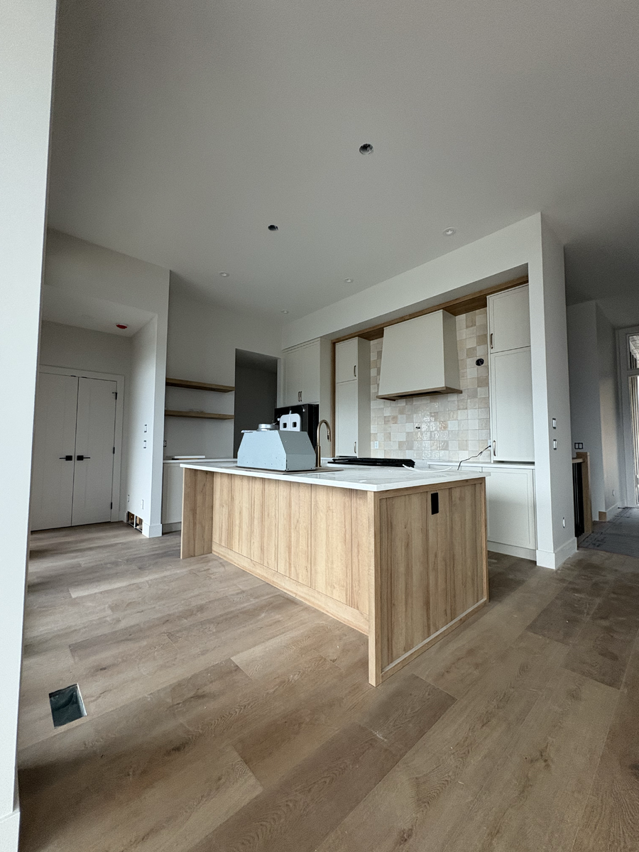 Wide angle of kitchen including island, construction still ongoing.