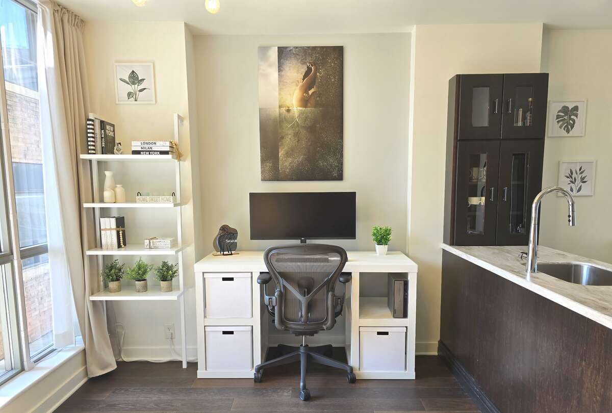 Bright office nook with large windows providing natural light, adjacent to a modern kitchen with ample storage.