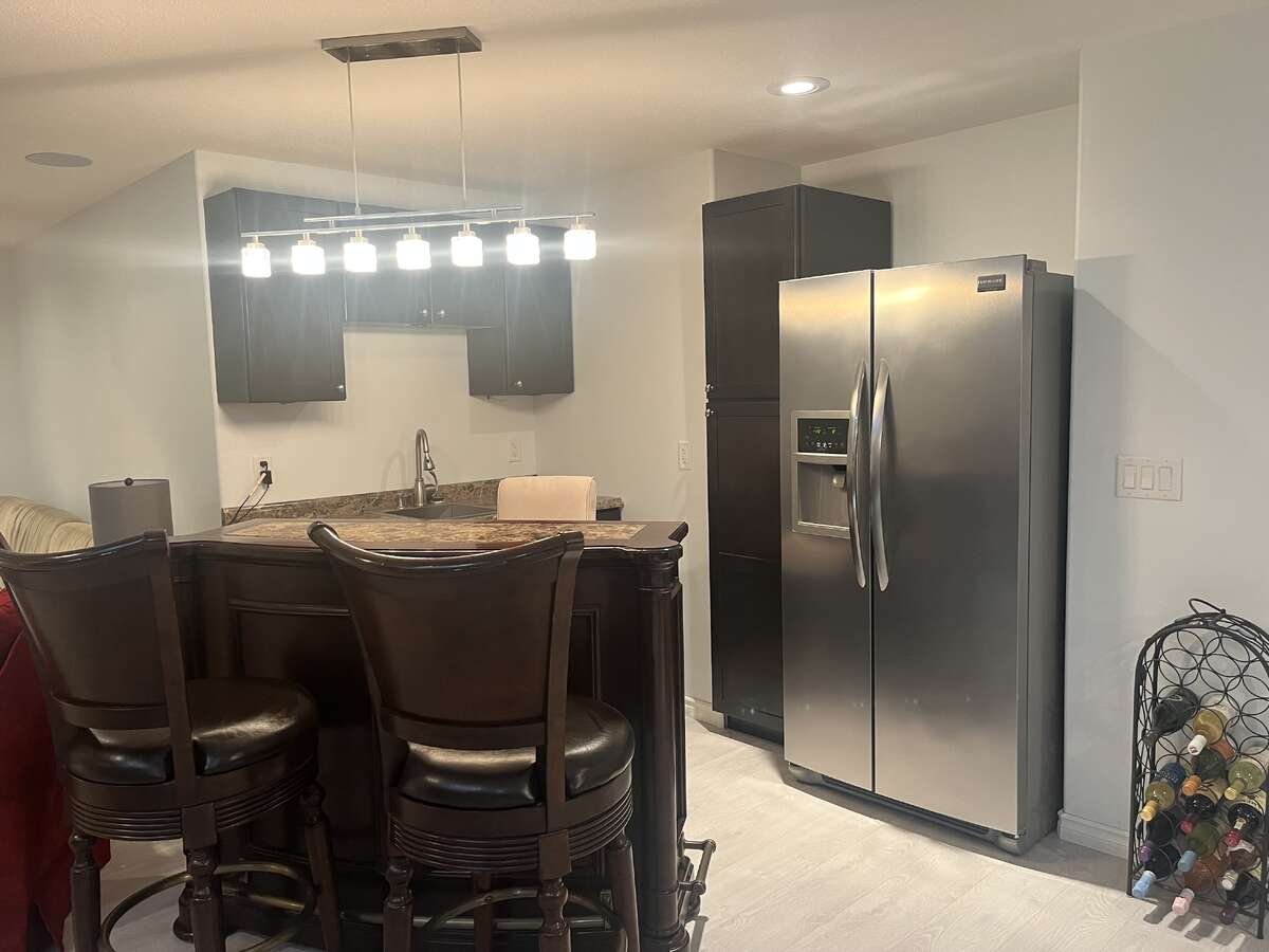 Full wet bar with stainless steel sink and fridge freezer, and multiple cupboards