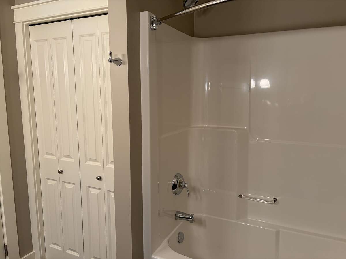 Shower/tub and linen closet in ensuite bathroom.