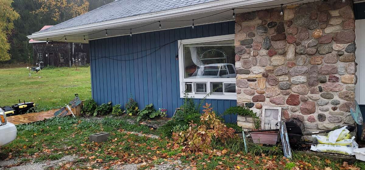 Driveway view of house with stone fireplace