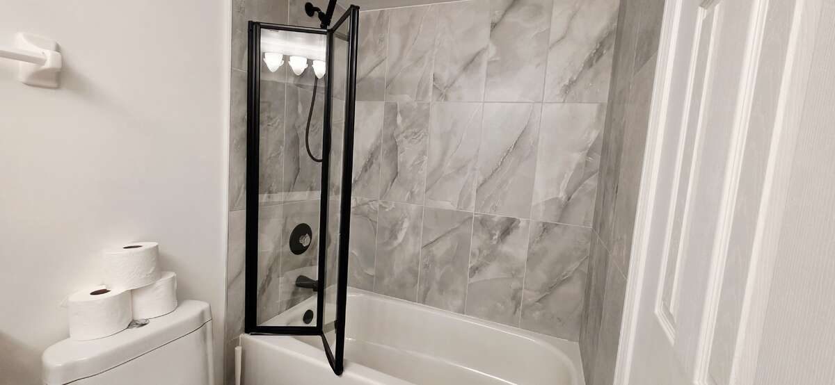 New primary bathroom wall and floor tiles with minimalist foldable glass tub enclosure