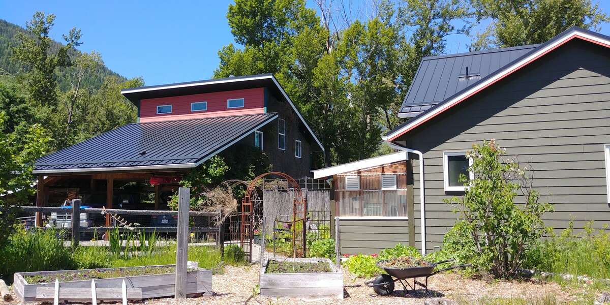 The carport/studio on the left, home with attached greenhouse to the right.